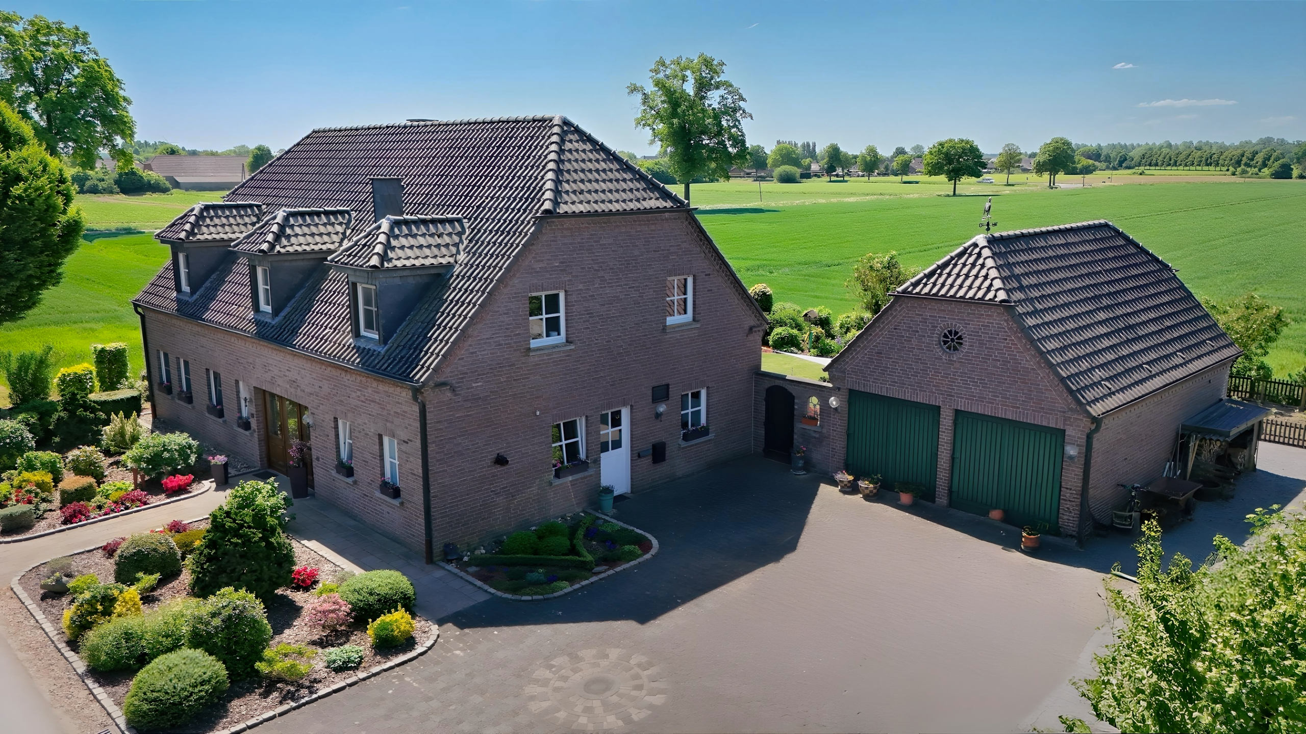 Ehemaliges Bauernhaus mit Doppelgarage und gepflegtem Vorgarten in ländlicher Umgebung bei Kevelaer – traditionelles Satteldach mit Gauben und Tondachziegeln.