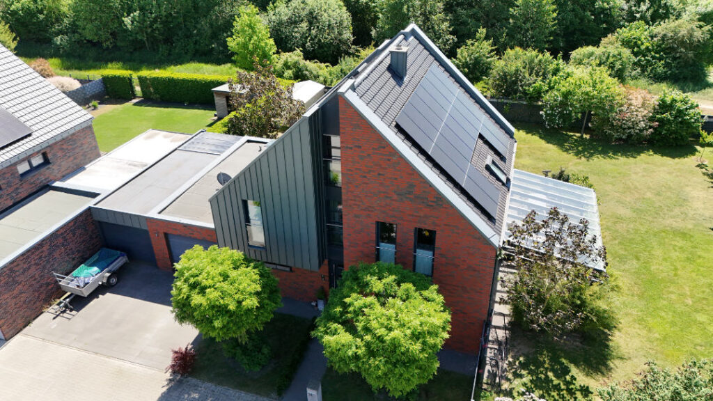 Einfamilienhaus mit moderner Photovoltaikanlage auf dem Ziegeldach in Kevelaer – Full-Black Solarmodule und Pultdach mit großer Glasüberdachung der Terrasse.