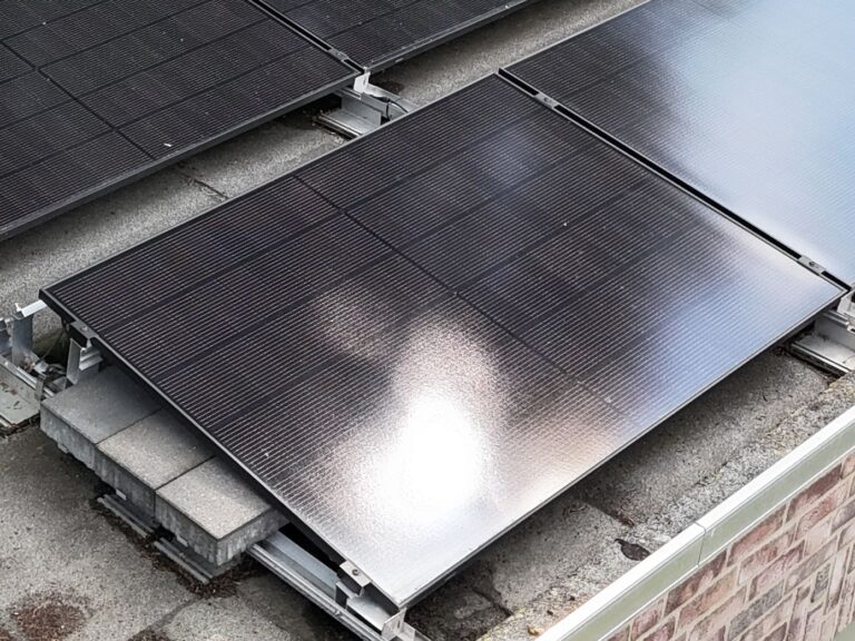 Detailaufnahme eines Full-Black Solarmoduls auf Flachdach – ballastierte PV-Unterkonstruktion mit Betonplatten zur sicheren Montage.