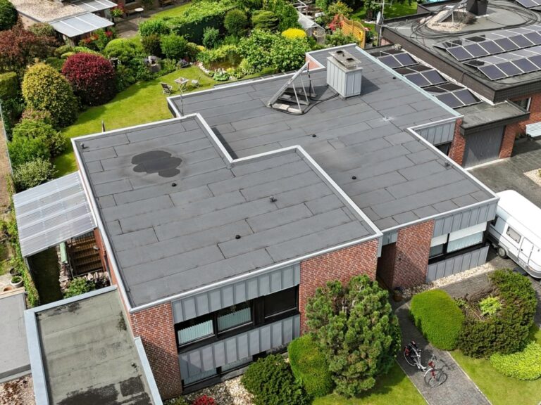 Flachdachsanierung mit hochwertigen Bitumenbahnen von Bauder – Wohnhaus mit Klinkerfassade und modernen Prefa Attikaabdeckungen in hellgrau