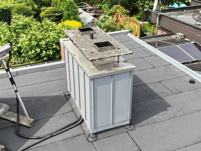 Flachdach mit Bitumenabdichtung und saniertem Schornstein in Prefa P.10 hellgrau – Detailaufnahme einer professionellen Dachsanierung